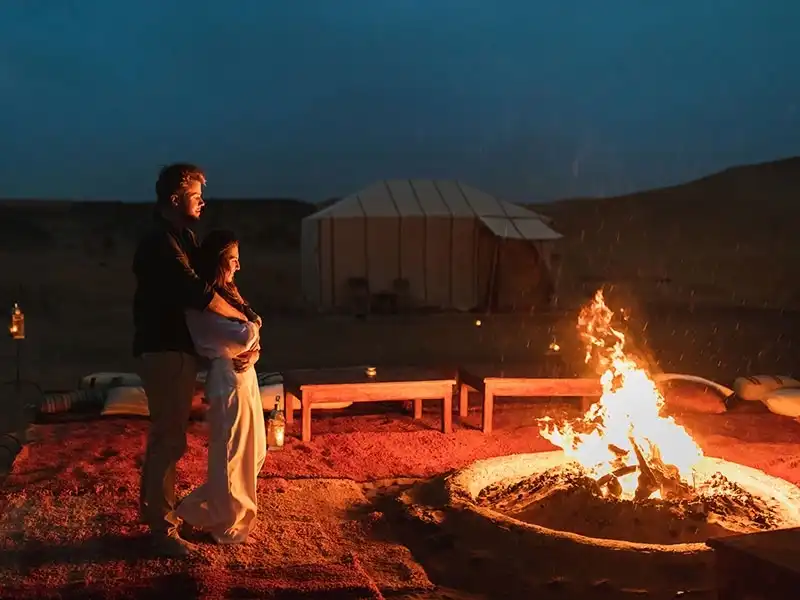 A couple by a campfire at a Sahara desert camp near Merzouga at night